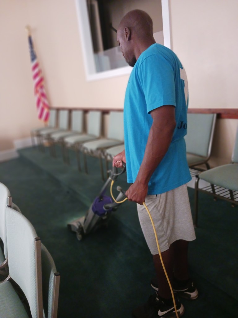A cleaner vacuuming the rug at a church.
