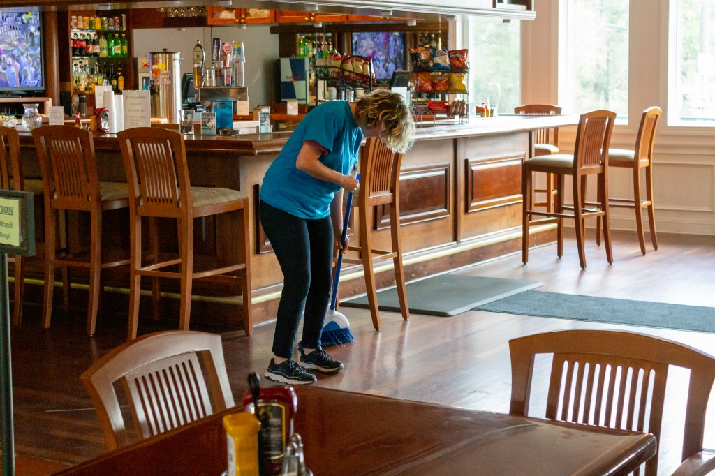 A cleaner sweeping a beautiful bar area.